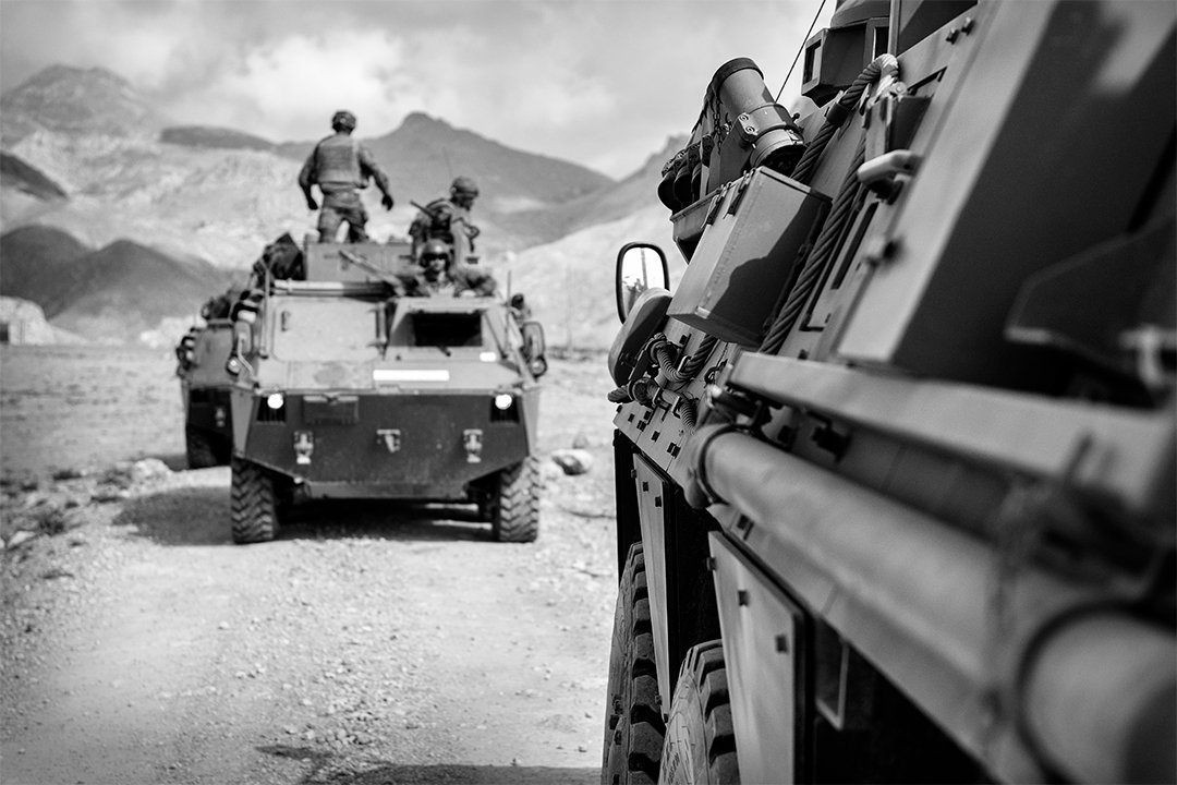Military vehicles travelling along a track.